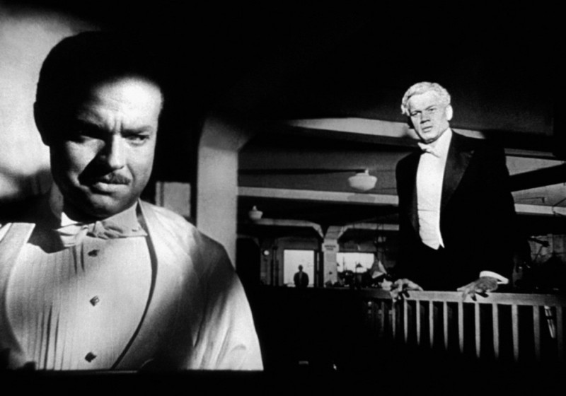 A shot with a deep depth of field from Citizen Kane, showing two men, one looking at the other and the other looking away.