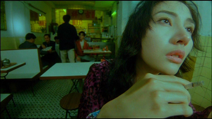 Wide Angle Lens shot from Wang Kar Wai's "Fallen Angels" of a woman close to the camera smoking a cigarette.